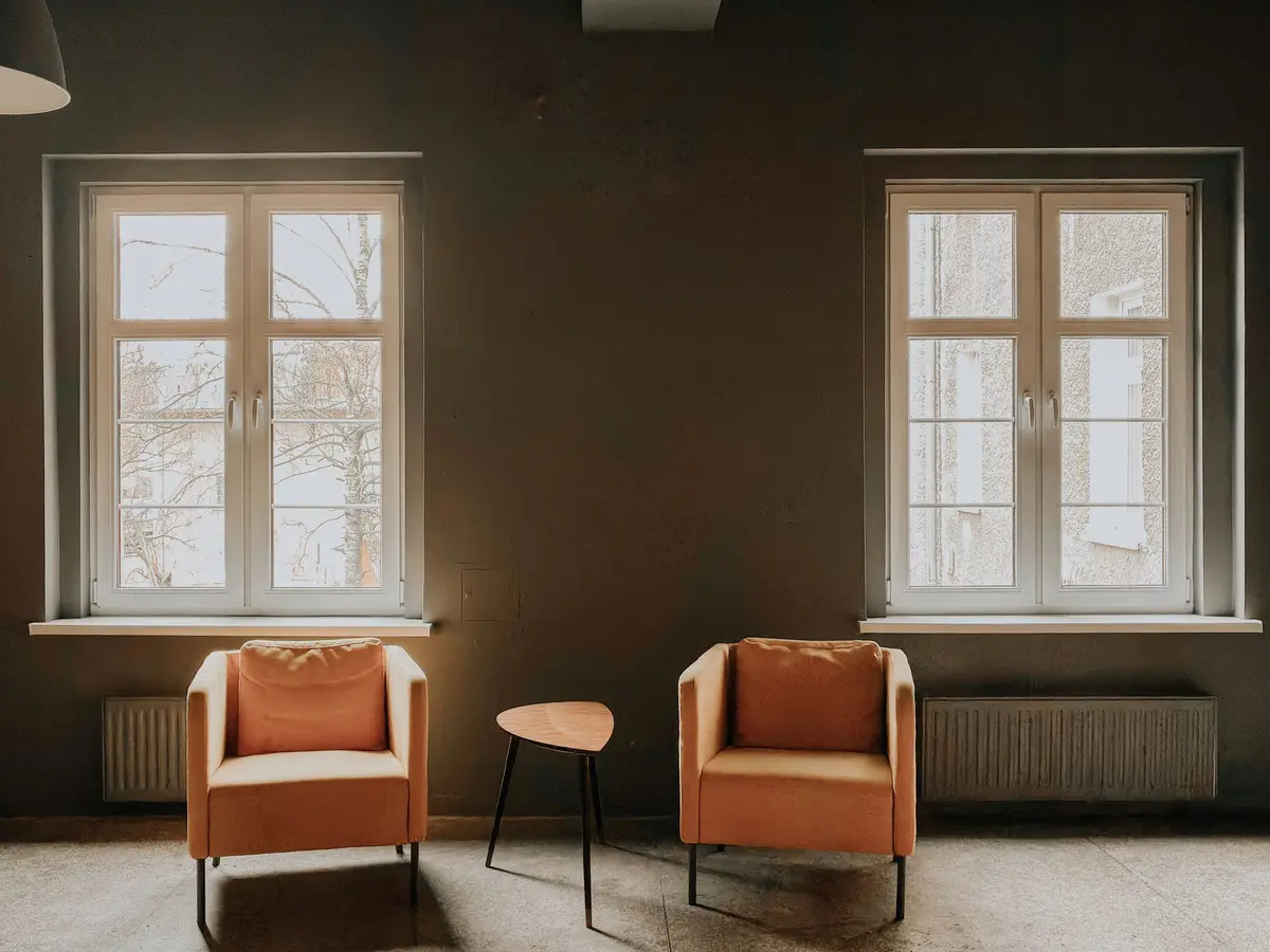 A calm room with two armchairs and tall windows