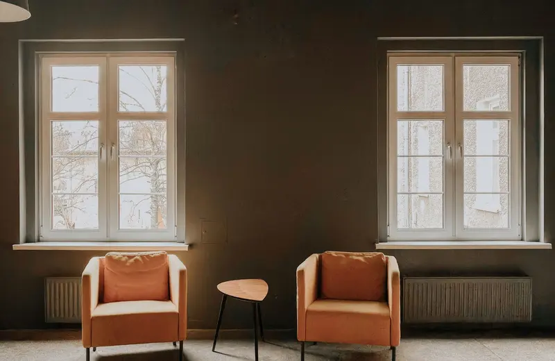 A calm room with two armchairs and tall windows