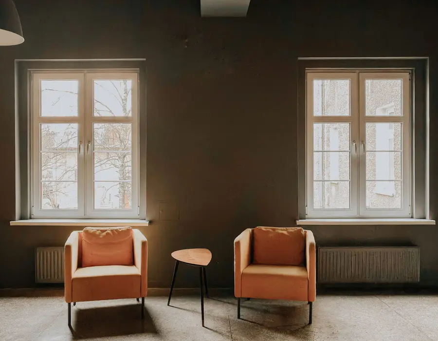 A calm room with two armchairs and tall windows