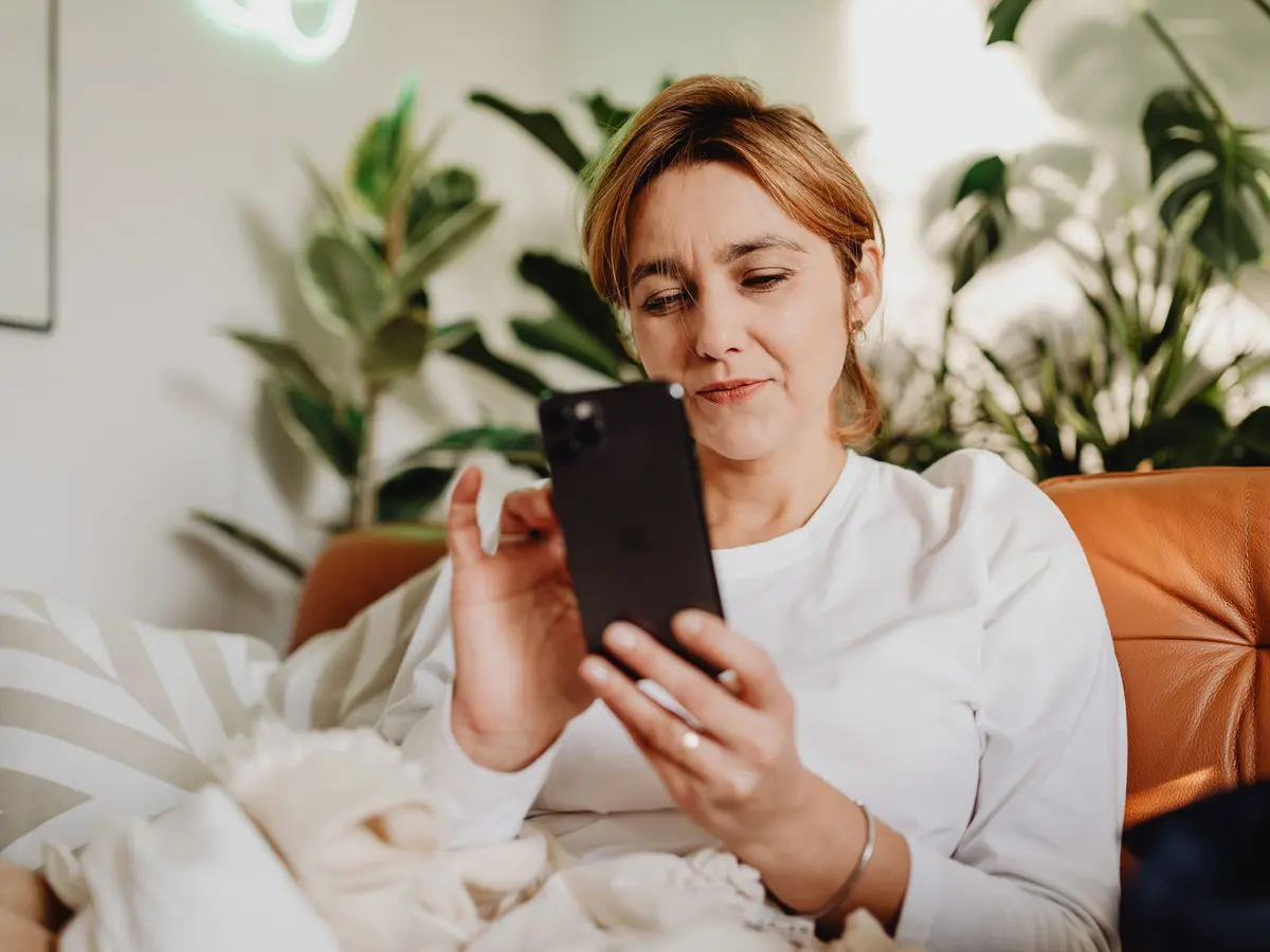 A woman looking at her phone at home.